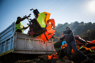 Greeks and volunteers try to clean up the beaches, and the only thing they can do with the fake life jackets is to burn them.