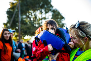 Three year old Rana is lifted from a boat by a volunteer.